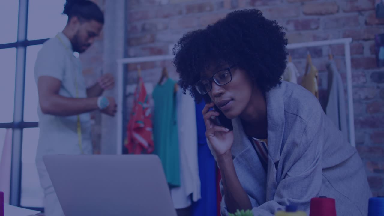 Designer leaning on laptop answering growing chat icons by calling while stylist measuring on rack