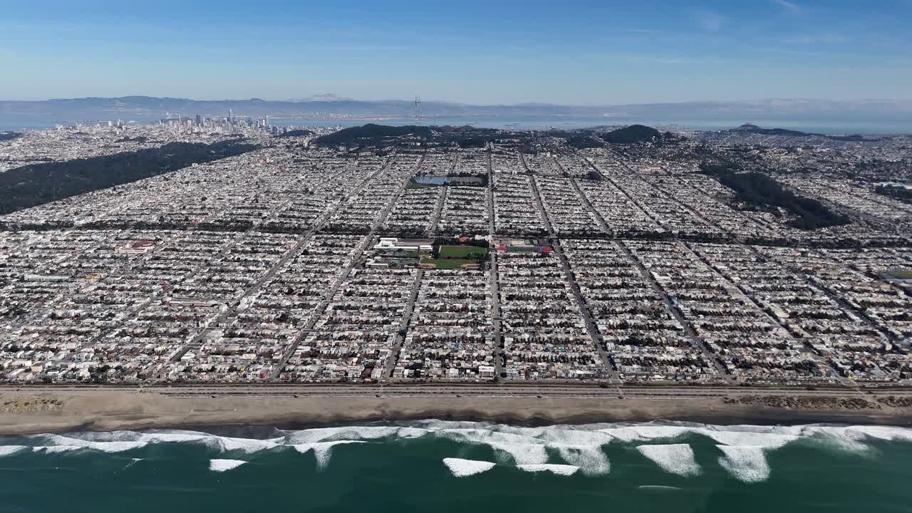 Aerial view of San Franciscoâ€™s structured grid layout, Ocean Beach, and lush Golden Gate Park, with the downtown skyline and bay in the distance.