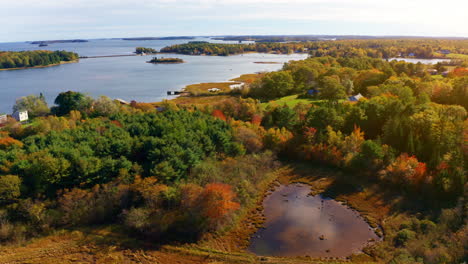 aerial drone shot over the coastline of oak island, nova scotia, canada.
high view of the sea, autumn colorful trees foliage. picturesque landscape. fall vibrant colors.