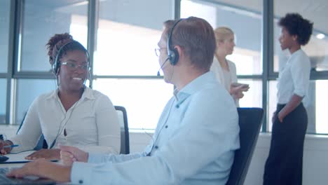 dos alegres agentes de ventas con auriculares sentados juntos