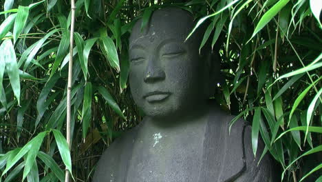 medium shot of statue of jizo surrounded by bamboo