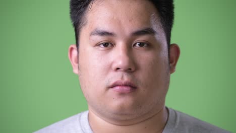 초록색 배경에 젊은 잘생긴 과체중 아시아인