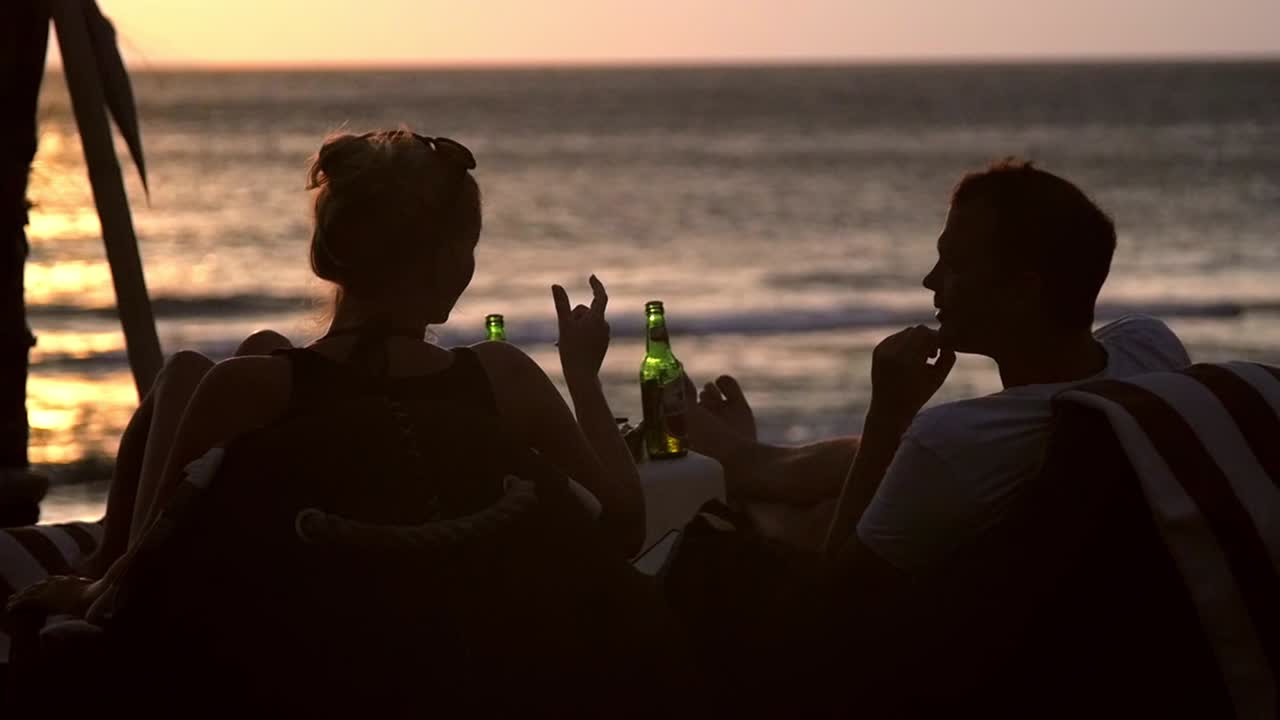 Homem e mulher na praia ao pôr do sol
