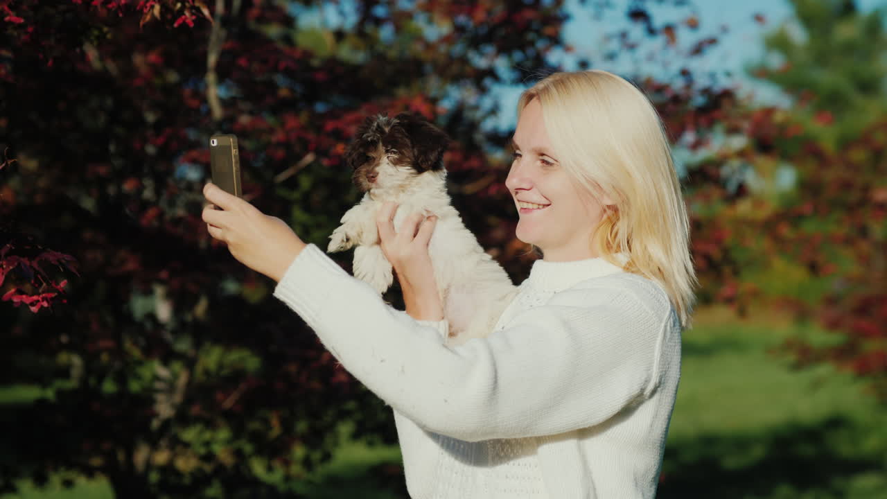 여자는 강아지와 함께 셀카를 찍는다