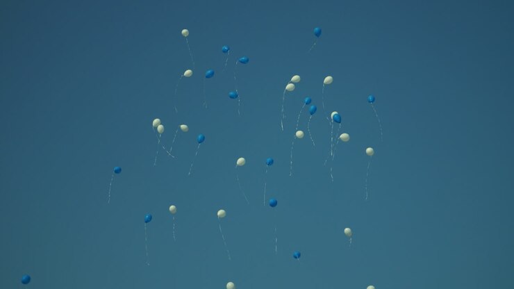 Palloncini per le feste che volano nel cielo blu. Palloncini bianchi e blu di compleanno nel cielo.
