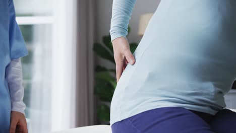 midsection of female patient showing female physiotherapist area of pain on back