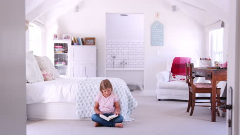 young white girl reading a book alone in her bedroom