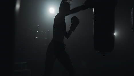 silhouette of a female boxer training with a punching bag