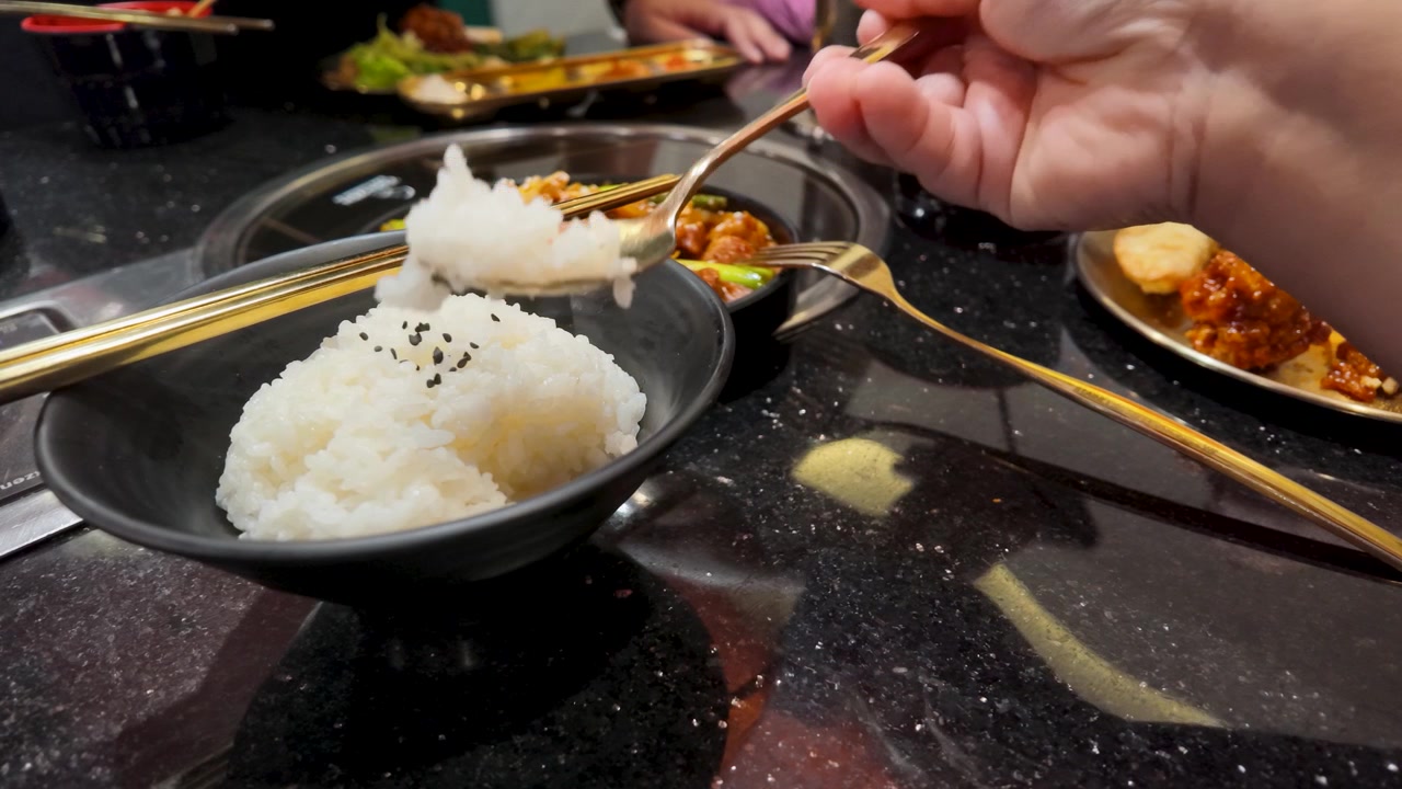 Person Scooping Steamed White Rice from a Bowl at a Restaurant