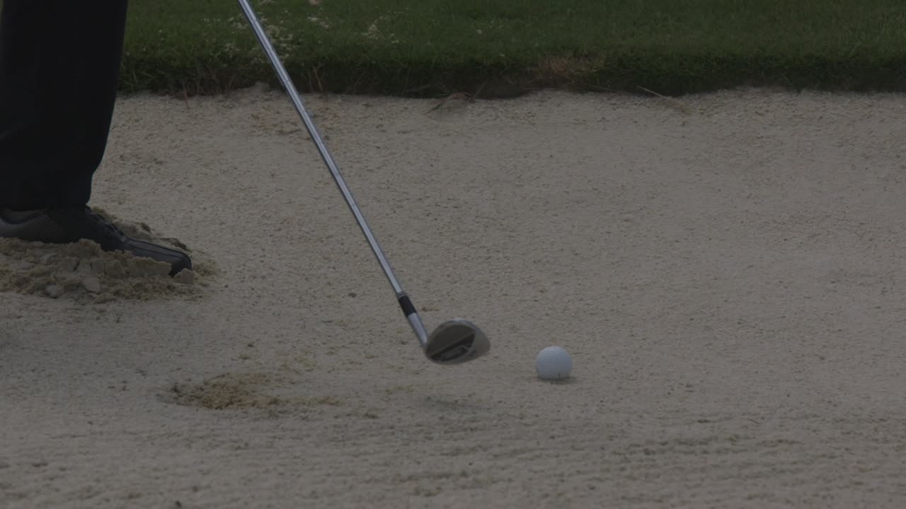 Colpire una pallina da golf nella sabbia.