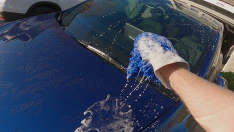 Brazo-De-Hombre-Lavando-Un-Auto-Azul-Con-Una-Mano-Azul-Mit