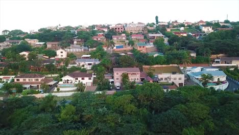 Drone-Volando-Sobre-Algunas-Coloridas-Casas-Residenciales-Con-Una-Ligera-Vista-Al-Mar-En-La-Distancia-En-El-Acantilado-En-Durban,-Sudáfrica