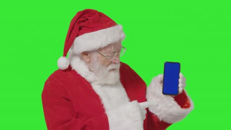 portrait shot of santa holding a blue screen mobile phone in front of green screen