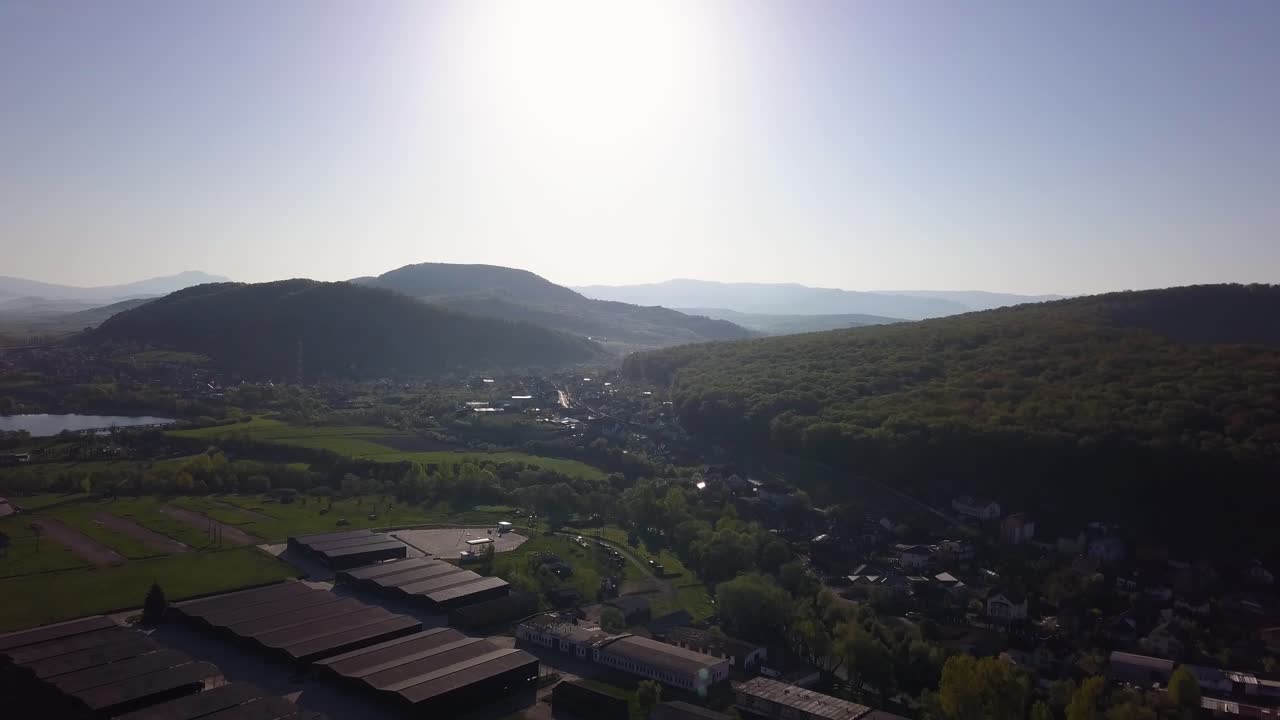 산업 건물 위를 날아다니는 드론, 천천히 내려와 풍경을 드러니다. 언덕과 숲이 있는 자연 풍경