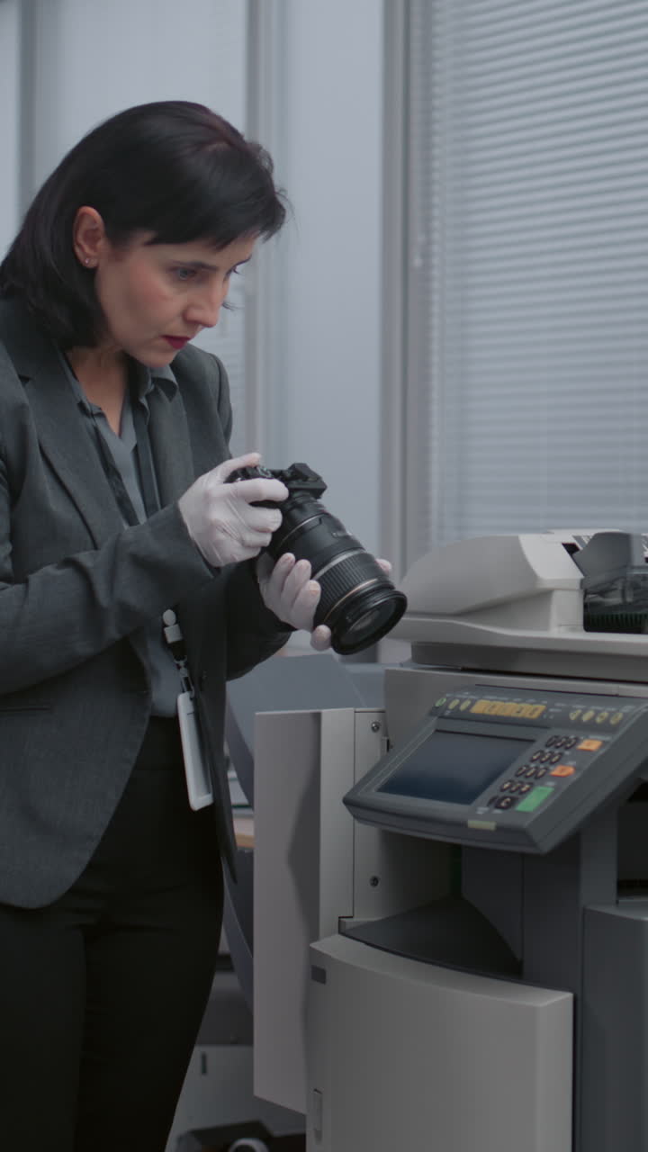 mujer de negocios inspeccionando la cámara cerca de una copiadora en una oficina