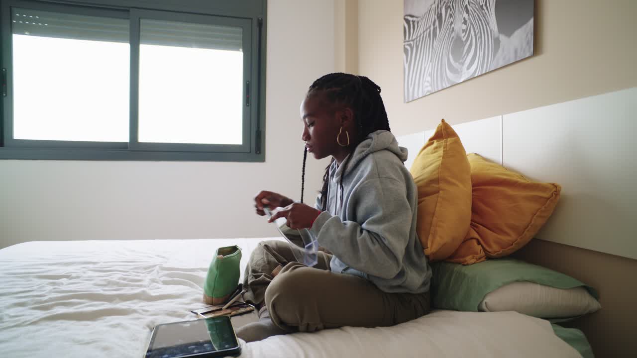 A young woman applying makeup in her bedroom