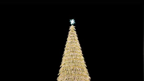 una instalación de árbol de navidad iluminada de oro se muestra durante la noche durante las festividades de navidad