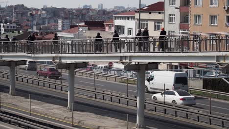 cityscape view of a pedestrian bridge over a highway with people crossing