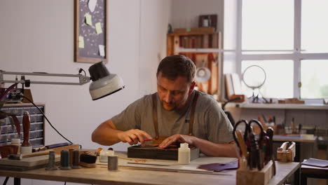 Man-adjusts-table-lamp-for-comfortable-leather-processing