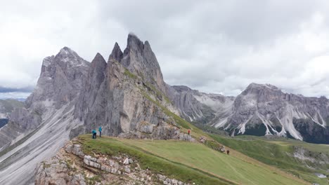 Gente-Caminando-A-Lo-Largo-De-Seceda-Con-Torres-De-Fermeda-En-El-Fondo,-Dolomitas,-Antena