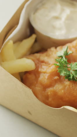 video of fish and chips with dip in takeaway food box, with copy space on white background