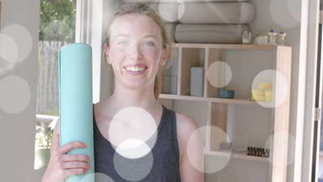 animation of light spots over happy caucasian teenage girl holding yoga mat