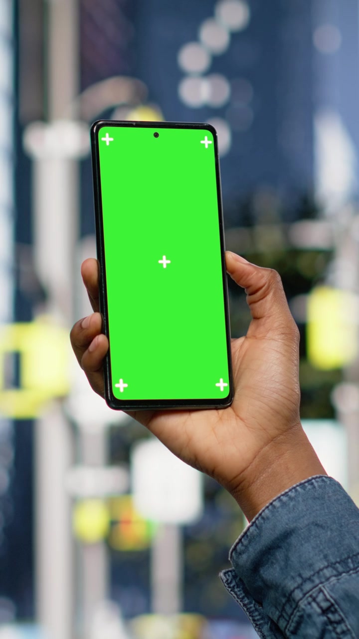Video verticale: Smartphone verticale con green screen usato da una donna afroamericana che cammina.