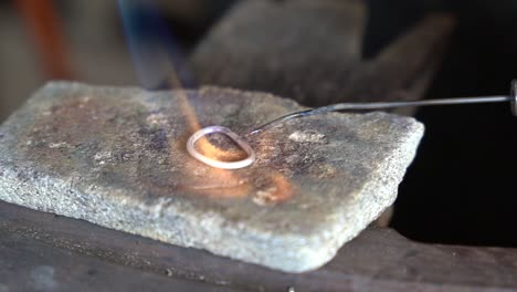 Torch-heating-and-melting-precious-metal-ring-for-creating-an-art-piece,-Close-up-view