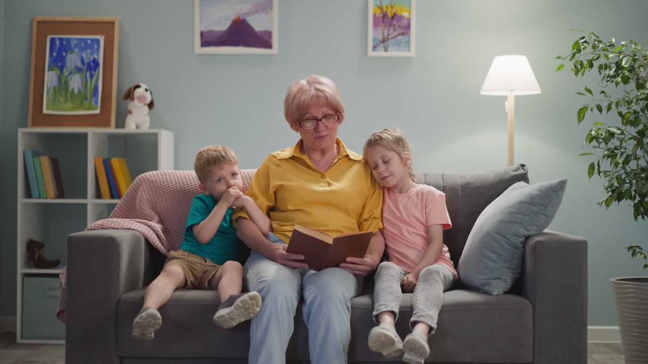 una vecchia signora carina con gli occhiali legge un libro ai bambini
