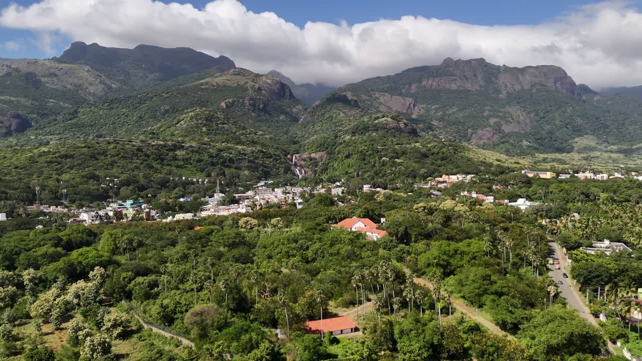 Mesmerising aerial footage of a lush South Indian town nestled at the foothills of the Western Ghats, surrounded by dense greenery and towering cloud-clad moving mountains