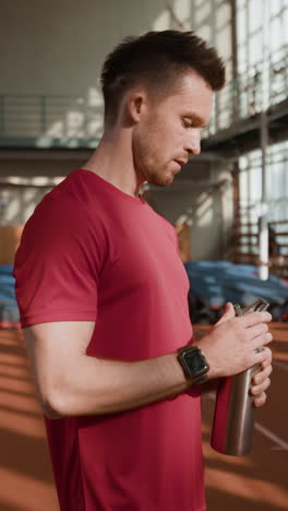 man taking a hydration break during workout at the gym