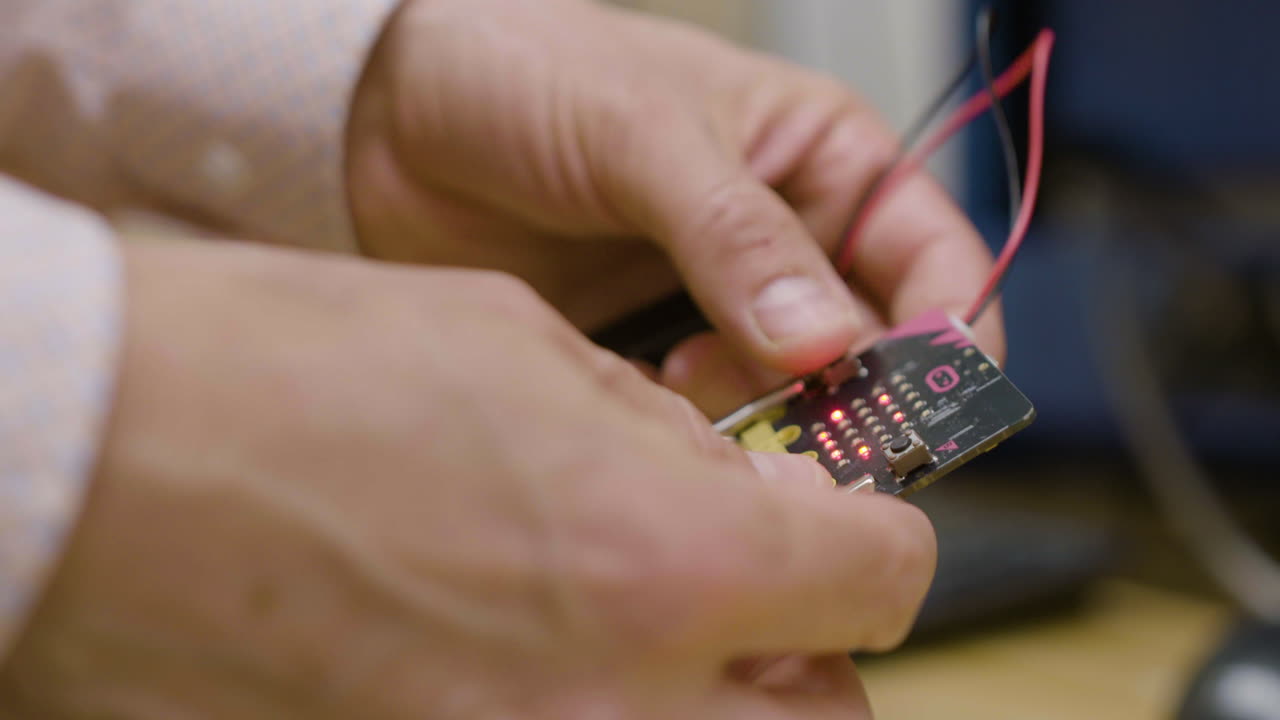 A man holds a single-board computer, examining it in his hands. The circuit board glows with illuminated LEDs.