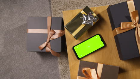 overhead shot of wrapped gifts or presents on table at home with green screen mobile phone