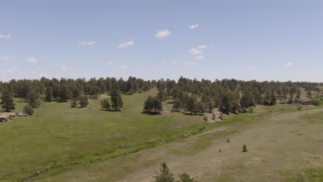 aerial views of a grassy plane heading to a beautiful rock formation in palmer lake colorado