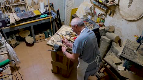 italian sculptor in his workshop working on a olive wood statue