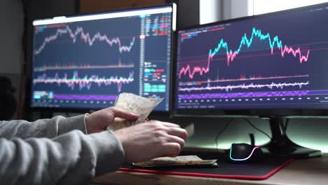 investor counts cash earnings in front of stock market screen