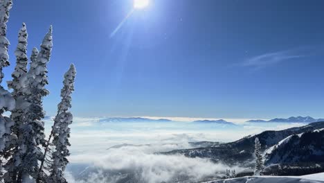 tilt up shot of a stunning winter landscape scene looking down at a cloudy snow covered valley from the summit of a ski resort in the rocky mountains of utah on a bright warm sunny spring day