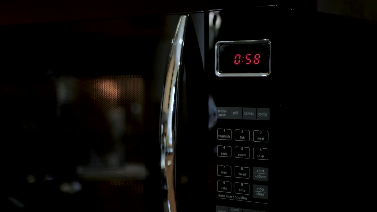 Un uomo imposta 1 minuto su un timer del forno a microonde