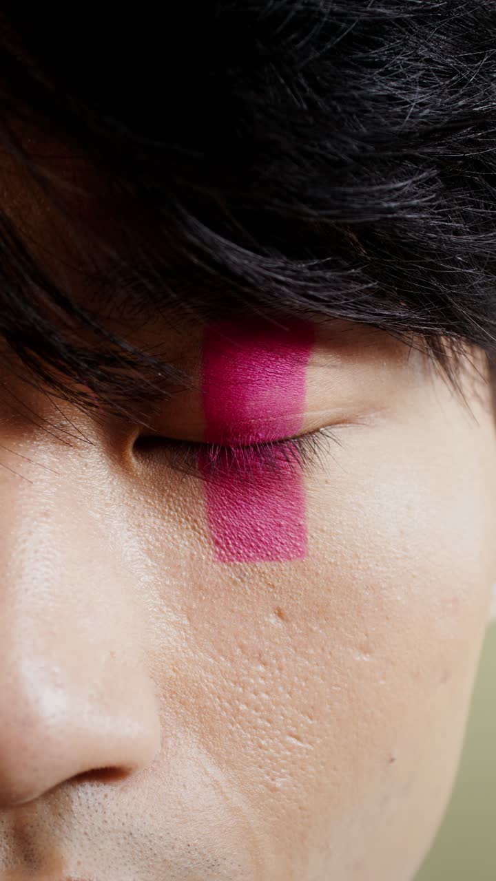 Primo piano del viso di un uomo con una striscia rosa sull'occhio