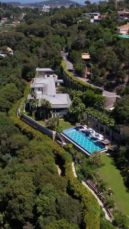 vertical drone shot of luxury villa with swimming pool on hill above cannes, france