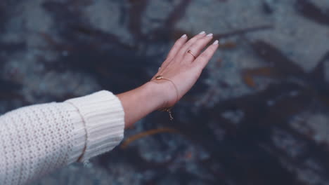 mujer de cerca agitando la mano sobre el agua del mar en la playa