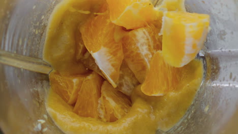 orange falling blended smoothie in mixer close up. citrus dropped in blender.