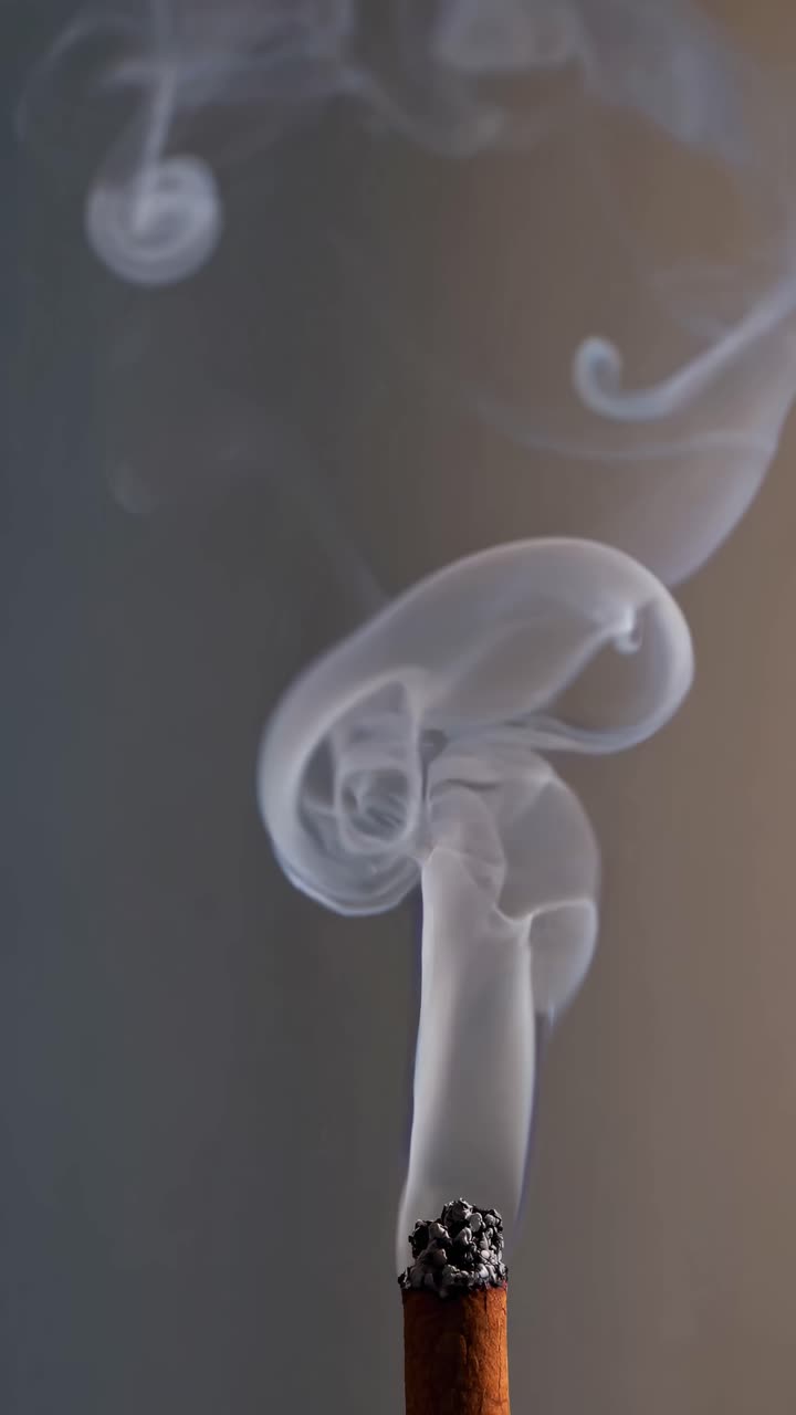Close-up shot of incense stick with swirling smoke against a dark background, creating a calming