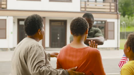 male soldier outside home going to military service while his family saying goodbye to him and his son waving usa flag