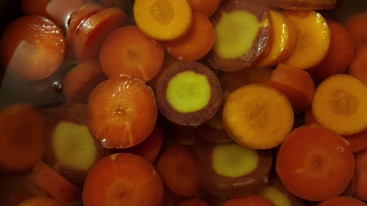 Chopped Heirloom Carrots boiling in water, close up, slow zoom in