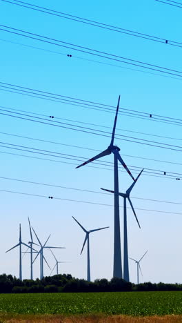 wind turbines and power lines at sunset. wind turbines stand tall in an open field under a clear blue sky, surrounded by power lines during twilight