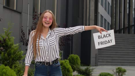 excited teen girl showing black friday inscription, advertising discounts, showing thumbs up