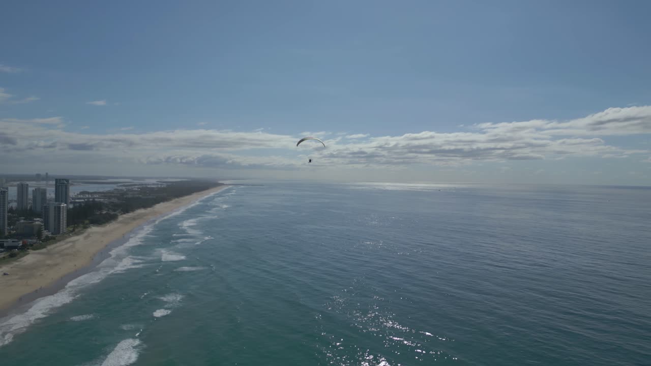 4k 드론은 고 은 날에 오스트레일리아의 골드 코스트 위에 있는 모터 패러글라이더를 따라갑니다.