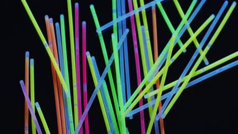 Animation-of-multiple-colorful-neon-glow-sticks-over-black-background