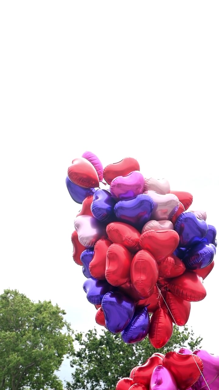 Mazzo di palloncini colorati a forma di cuore che fluttuano contro un cielo luminoso